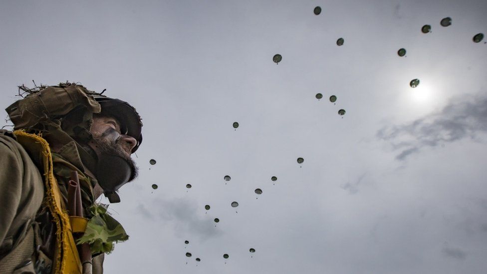 Parachutist watches others drop to the ground