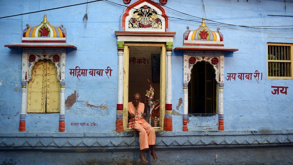 A priest sits in front of a Hindu temple