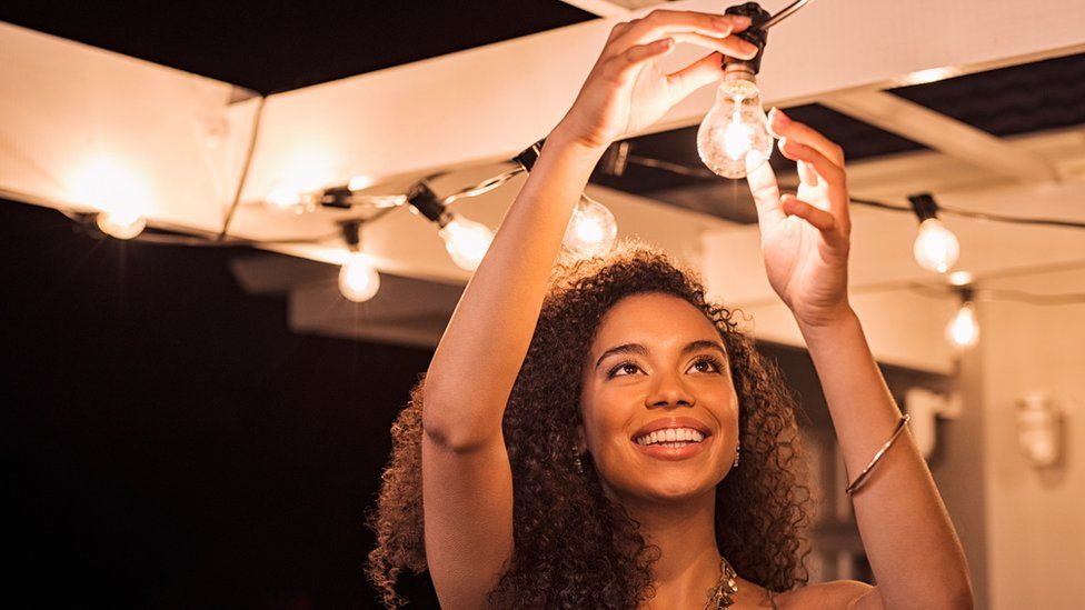 A woman putting in a lightbulb