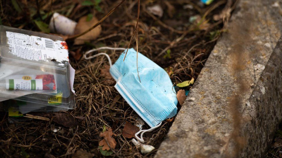 face mask sits among other discarded plastic waste