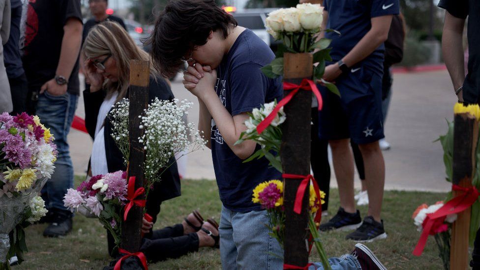 Mourners pray at a memorial to for the victims of the shooting at a mall in Allen, Texas