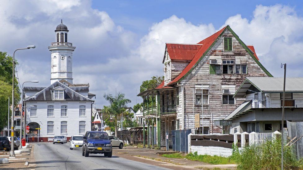 White wooden clock tower of the Ministry of Finance building and colonial houses in the city centre of Paramaribo