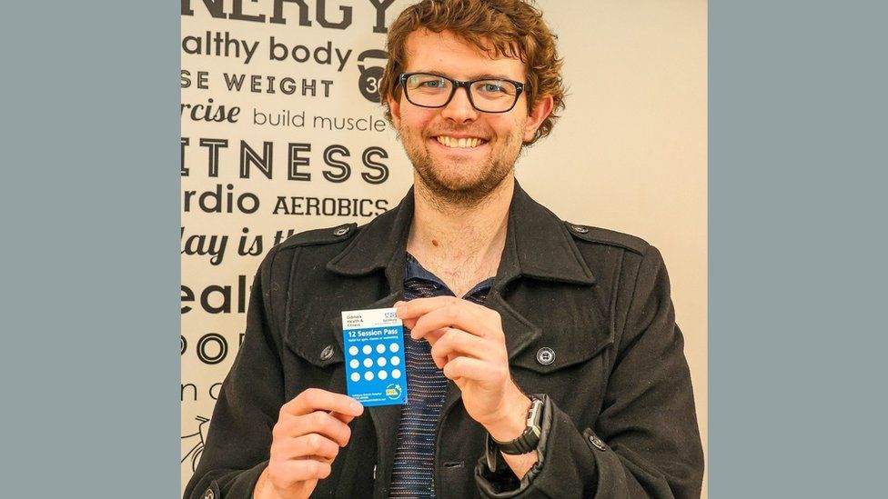 Charles McGrath smiling at the camera holding his free gym pass