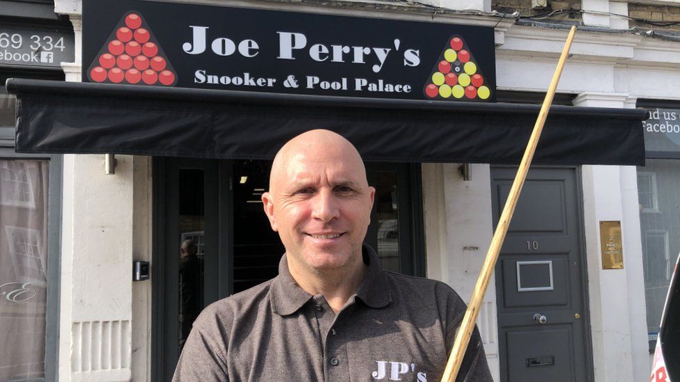 Joe Perry stood with a cue outside of his new snooker and pool club
