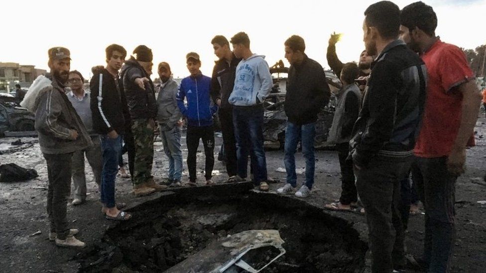 Locals look at debris at the scene of a massive car bomb in southern Baghdad(16 February 2017)
