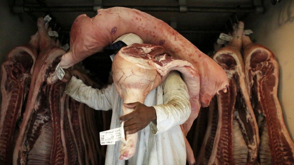 An employee carries pieces of meat at a butchery in Sao Paulo, Brazil October 10, 2014.