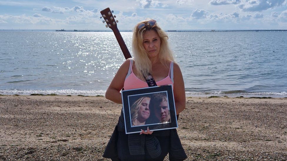 Emma Cain standing on Southend seafront with a picture of her son, Jon Cain