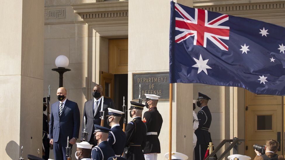 Министр обороны Австралии Питер Даттон и его американский коллега Ллойд Остин стоят на церемонии у здания Пентагона, посвященной визиту австралийца