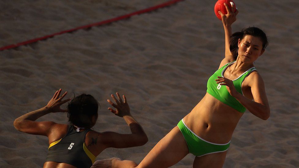 Shen Ping of China is seen shooting a ball during the Women's Handball Final at the 2nd Asian Beach Games in Muscat. The player is sporting a green bikini.