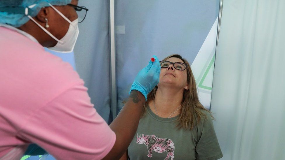A healthcare worker collects a swab from Bronwen Cook for a PCR test against the coronavirus disease (COVID-19) before traveling to London, at O.R. Tambo International Airport in Johannesburg, South Africa, November 26, 2021