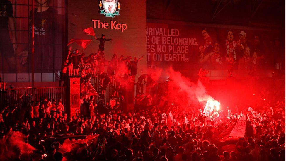 Crowd of Liverpool fans in front of The Kop celebrating Premier League title win