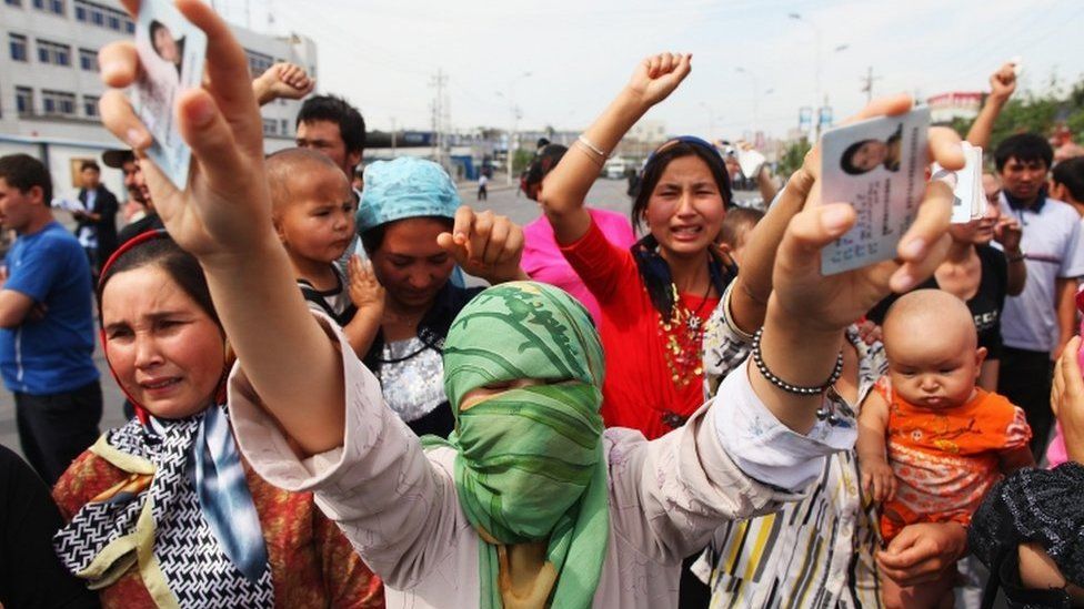 An Uighur woman holds the IDs of her relatives who are currently detained, as she and others protest on a street in July, 2009