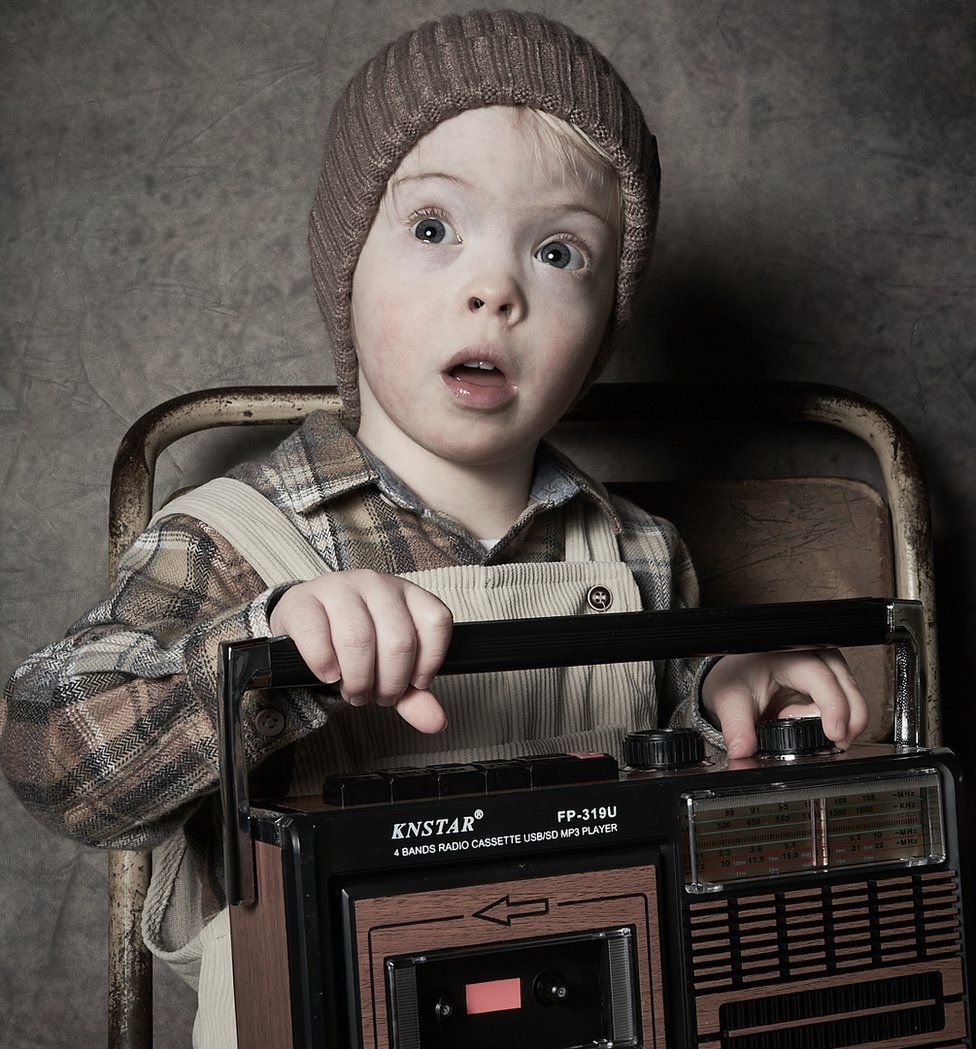 A young boy holds an old radio