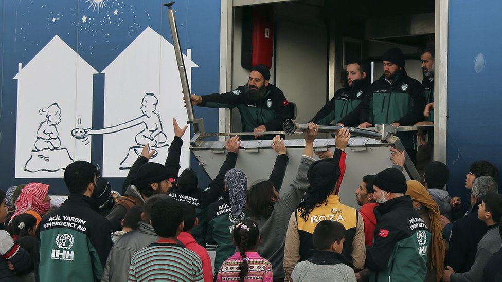 Syrian refugees receive aid near the Bab al-Salam crossing, opposite Turkey's Kilis province, 7 February