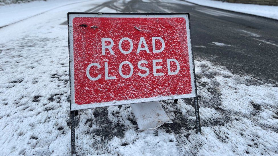 Road closed sign covered in snow