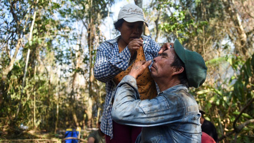 A woman helps a man apply eye drops after fighting a forest fire in the community of Bella Altura, San Buenaventura