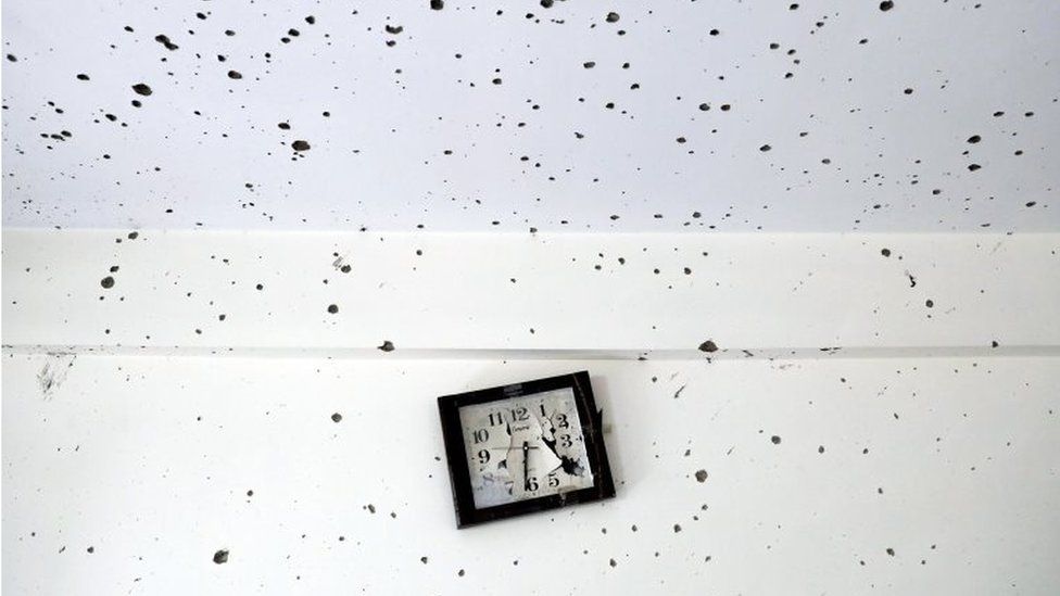 A damaged clock is seen inside a classroom after the attack at the university of Kabul