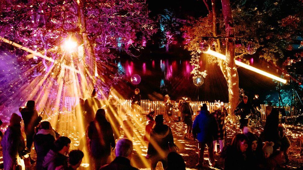 People walking past illuminated trees at Windsor Great Park