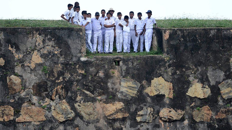 Sri Lankan schoolchildren stand on top of a 17th century Dutch fort overlooking Galle Stadium as they watch the fourth day of the opening Test match between Sri Lanka and Bangladesh in Galle (March 10 2017)
