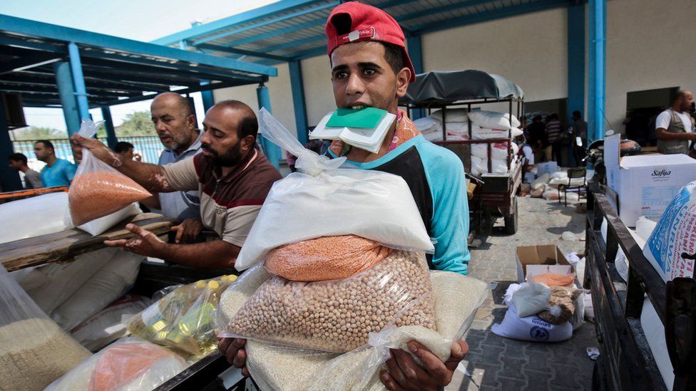 Palestinian men collect bags of food from a Unrwa compound in the southern Gaza Strip, 1 September 2018