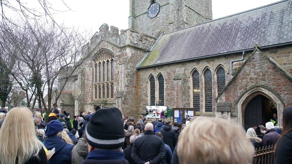 Crowds gathered outside the church watching the service on a screen