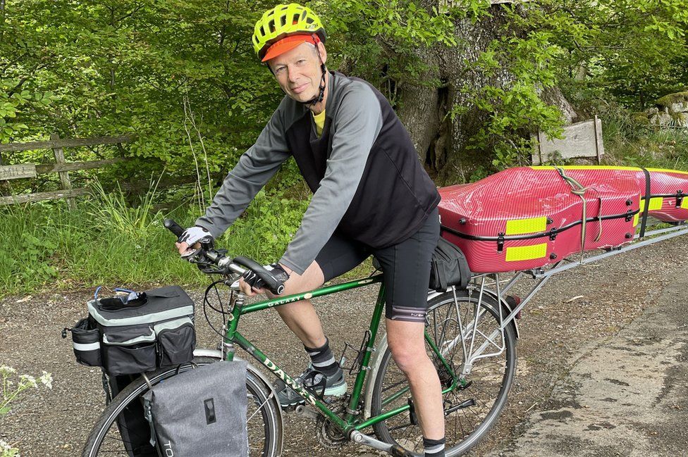 Kenneth on bike with cello behind