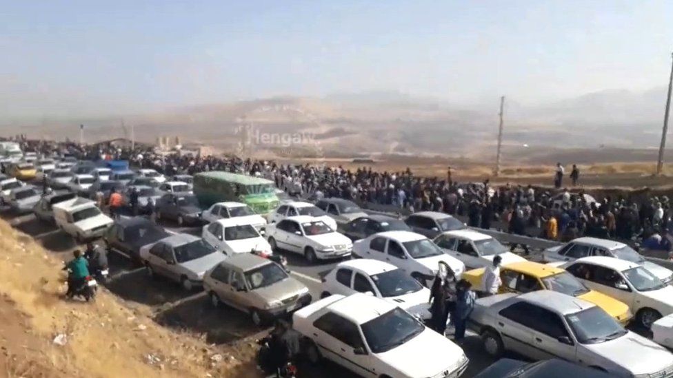 Screengrab of video posted by Kurdish rights group Hengaw purportedly showing people walking past queuing cars to reach the Aichi cemetery in Saqqez, Iran, to mark the 40th day of mourning for Mahsa Amini (26 October 2022)