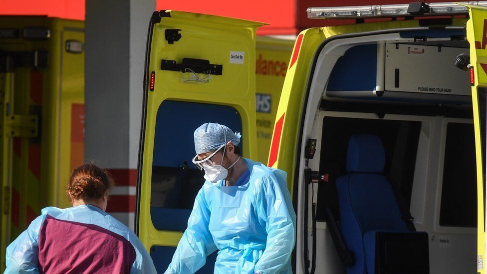 Doctors wearing protective equipment are seen loading a patient in to an ambulance outside St Thomas' Hospital in London