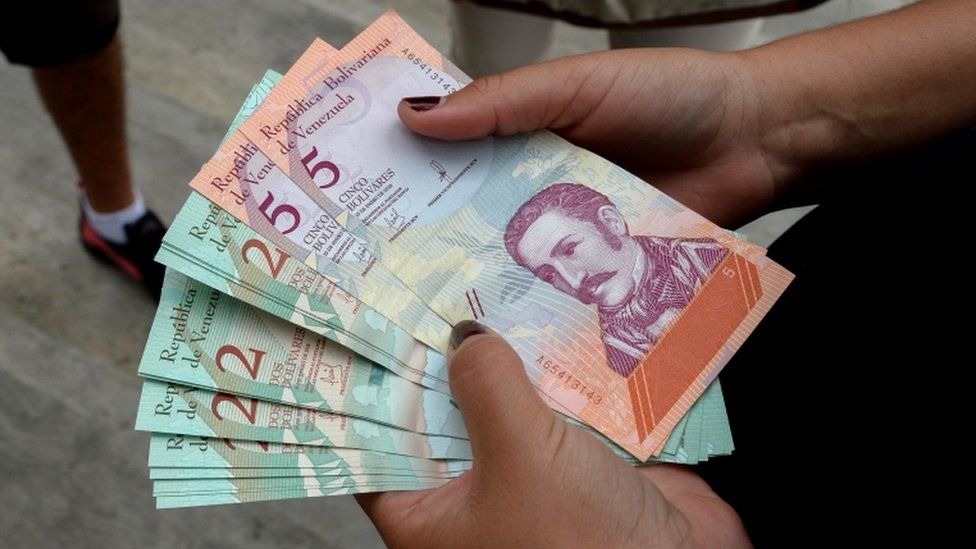 A woman holds new bolivar notes in downtown Caracas on 21 August, 2018.