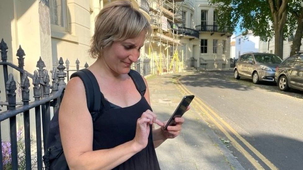 Emma Cohen en una calle, intentando enviar un mensaje con su teléfono