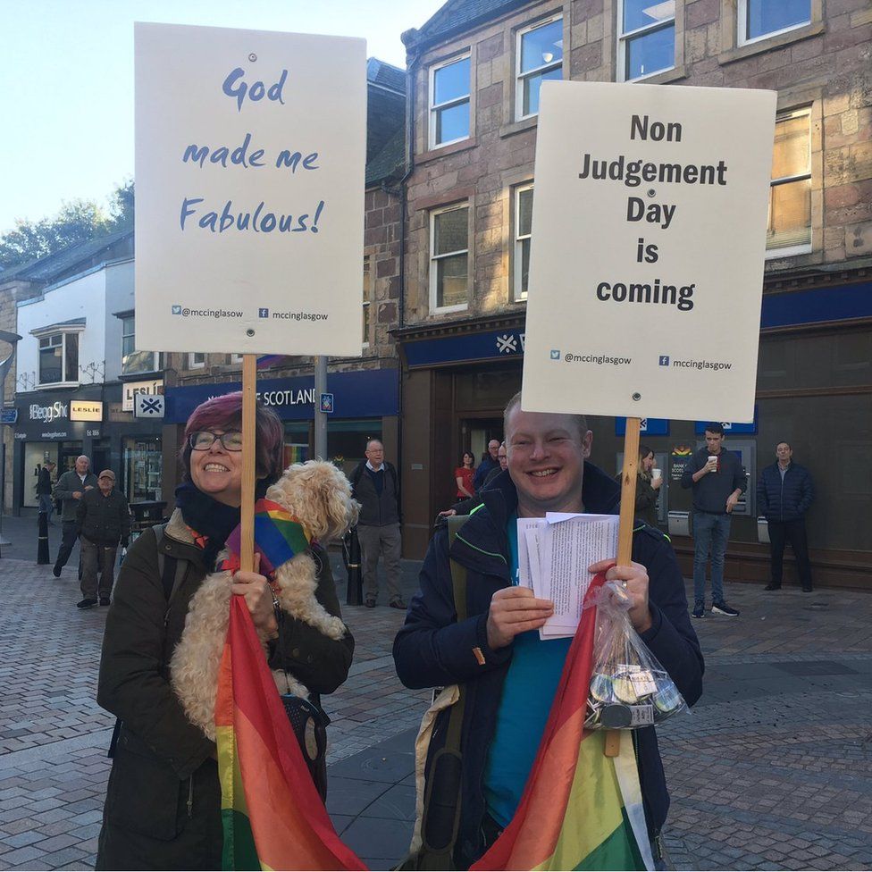 Two people holding placards at Pride in Inverness