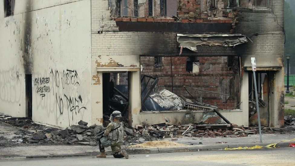 Un oficial de la Guardia Nacional frente a un edificio incendiado en Minneapolis.