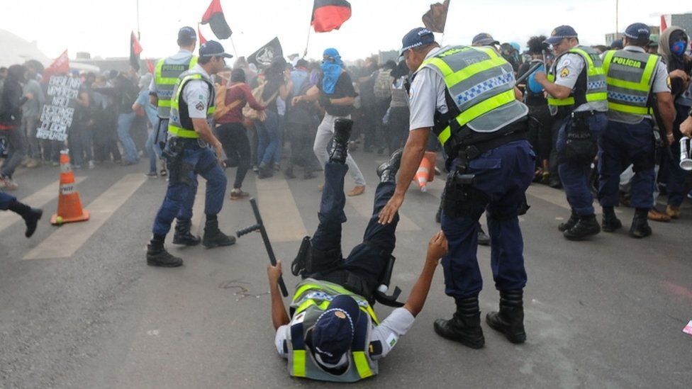 A police officer is knocked down during clashes with demonstrators protesting in front of the National Congress in Brasilia