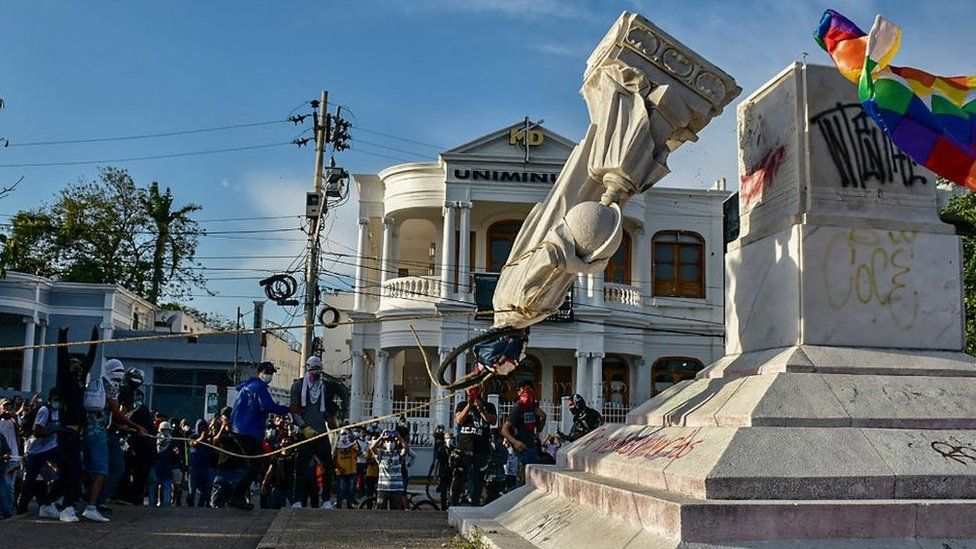 Протестующие сбивают статую Христофора Колумба во время демонстрации против правительства в Барранкилье, Колумбия, 28 июня 2021 года.