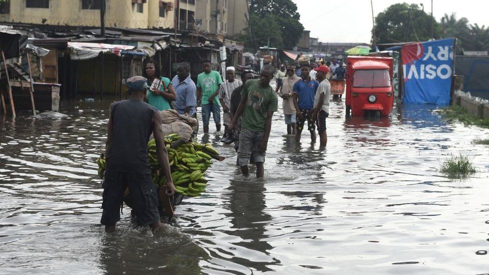 People walk on a flooded road at Okokomaiko in Ojo district of Lagos, on May 31, 2017.