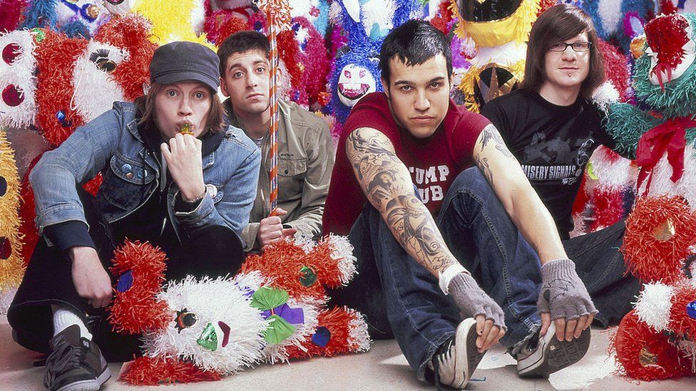 Fall Out Boy pictured in 2005. The band made up of singer Patrick Stump, bassist Pete Wentz, drummer Andy Hurley, and lead guitarist Joe Trohman are pictured sitting on the floor surrounded by colourful pinatas