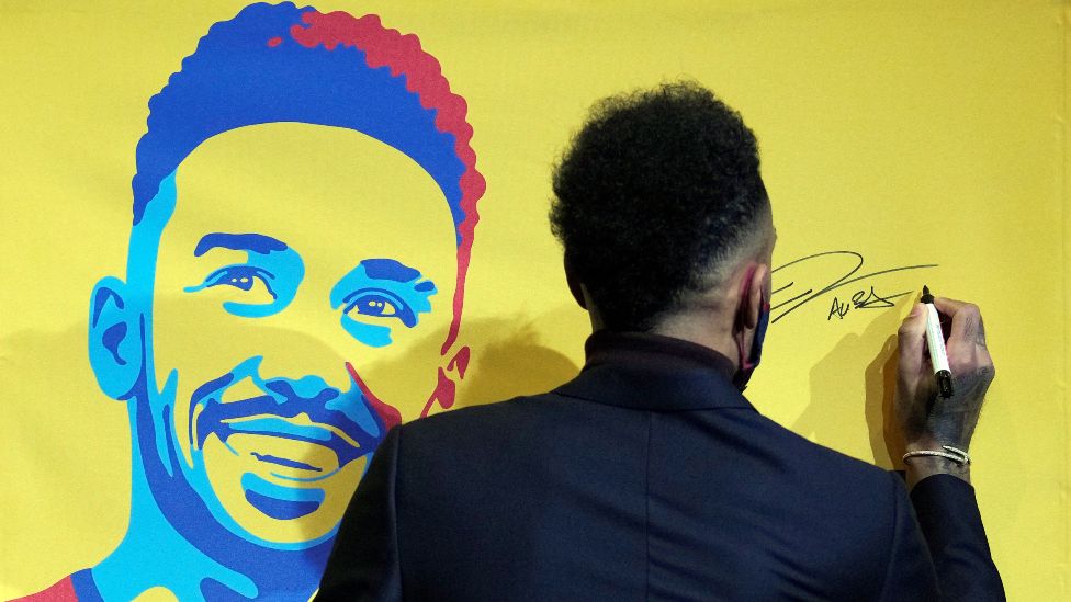 Pierre-Emerick Aubameyang signs his name on a poster of his image in Barcelona, Spain - Thursday 3 February 2022