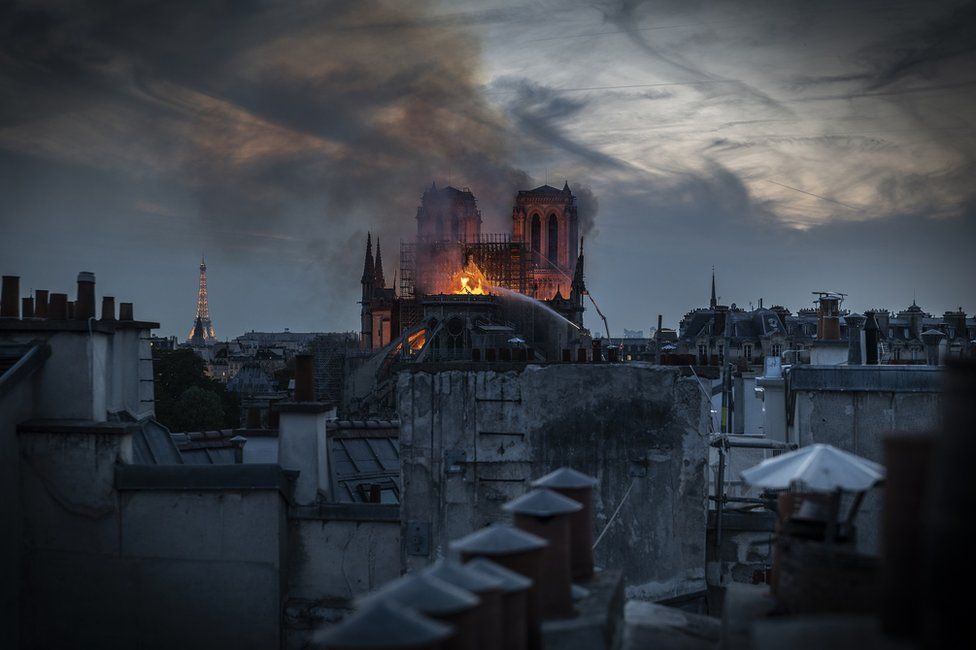 Flames and smoke are seen billowing from Notre-Dame's roof