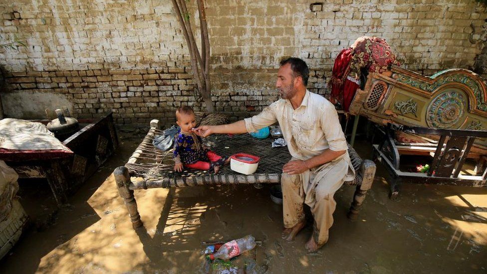 Мужчина кормит своего ребенка после наводнения в районе Чарсадда, провинция Хайбер-Пахтунхва, Пакистан, 28 августа 2022 г.