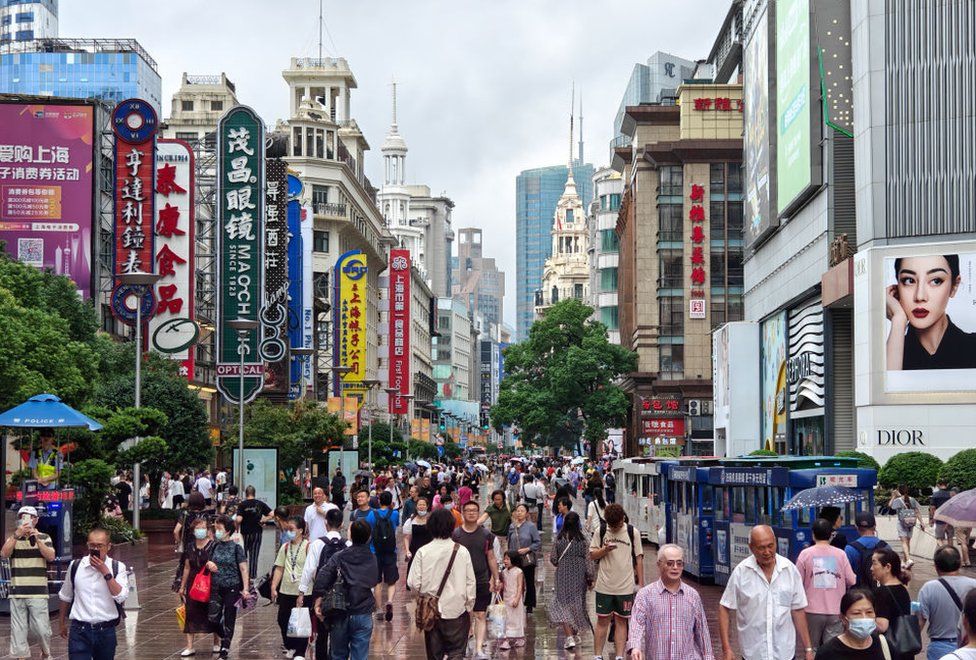 Туристы посещают пешеходную дорожку Нанкинской дороги под дождем в Шанхае, Китай, 14 сентября 2023 года.