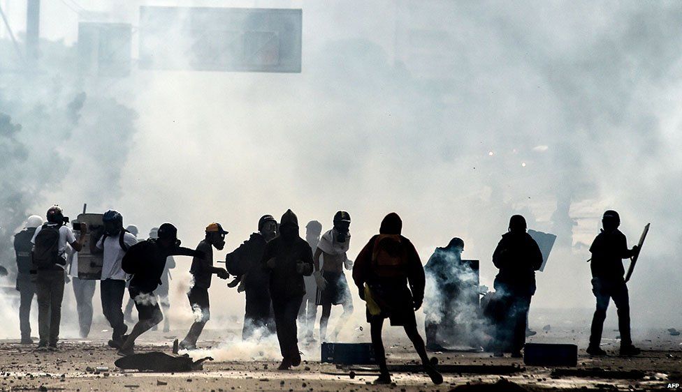 Anti-government protesters and police are shrouded by teargas during a demonstration which blocked the Francisco Fajardo highway in Caracas in May 2017
