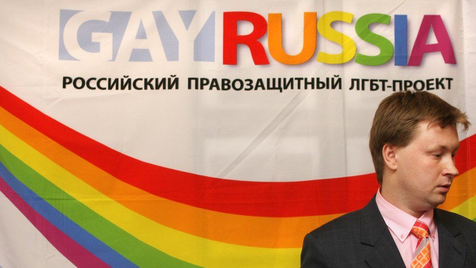Nikolai Alexeyev in front of a banner for the Gay Russia organisation