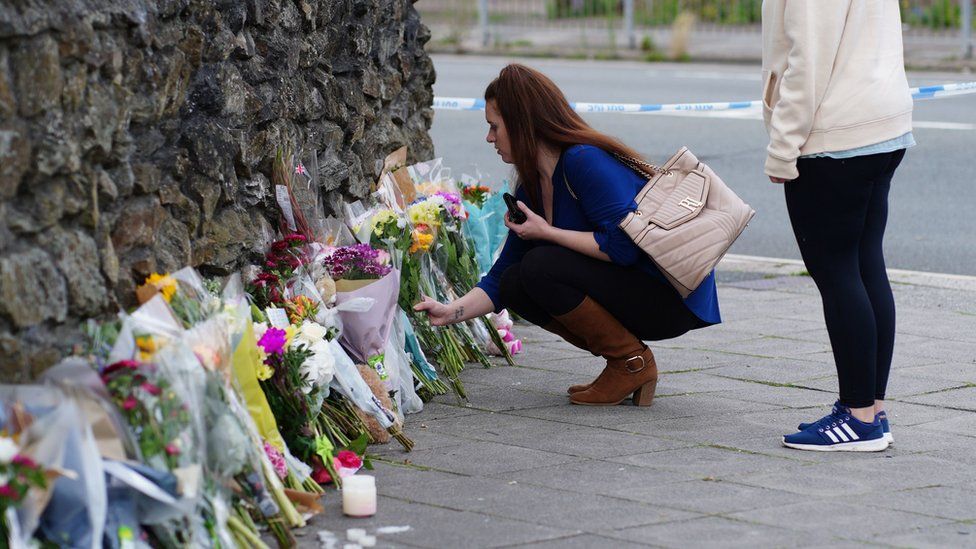 Люди возлагают цветы в память о жертвах стрельбы