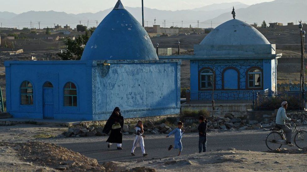 People walk past a shrine in Ghazni