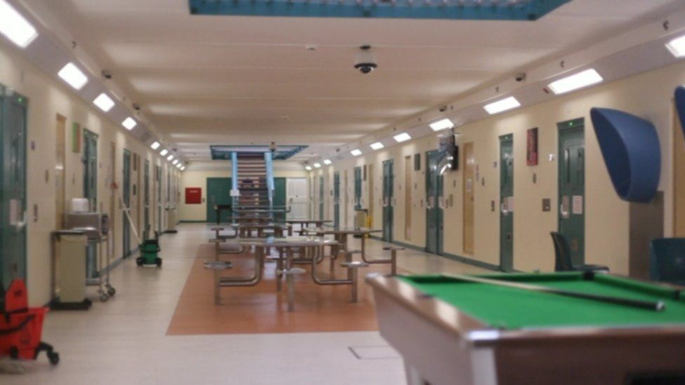 Inside Maghaberry prison, prison tables, chairs and snooker table, with cell doors along sides of room.