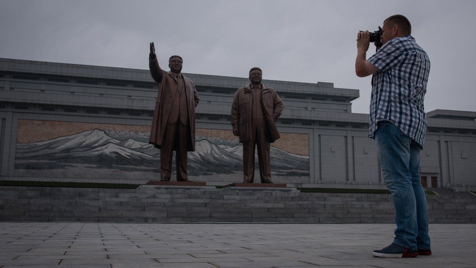 A tourist takes a photo of statues of late North Korean leaders Kim Il-Sung (L) and Kim Jong-Il (R), on Mansu hill in Pyongyang on July 23, 2017