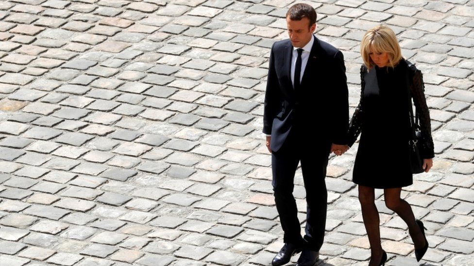 Mr Macron and his wife Brigitte holding hands