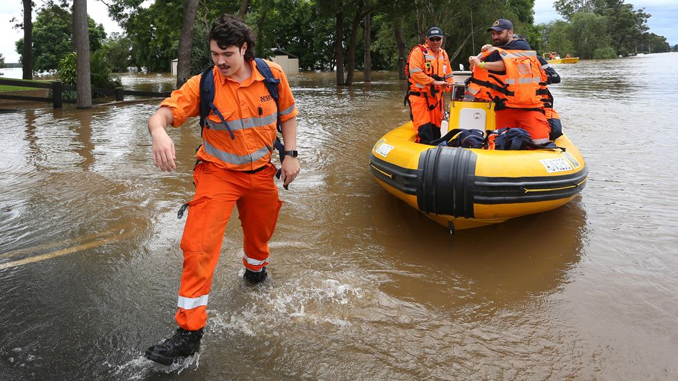Emergency workers step through a flooded street
