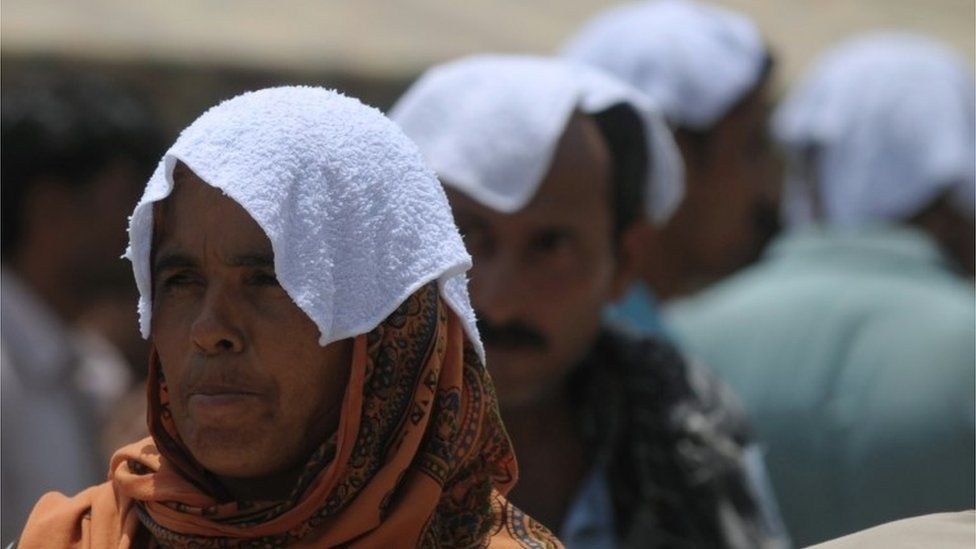 Pakistani relatives of heatstroke victims, their heads covered with wet towels, wait outside a hospital during a heatwave in Karachi on June 29, 2015.