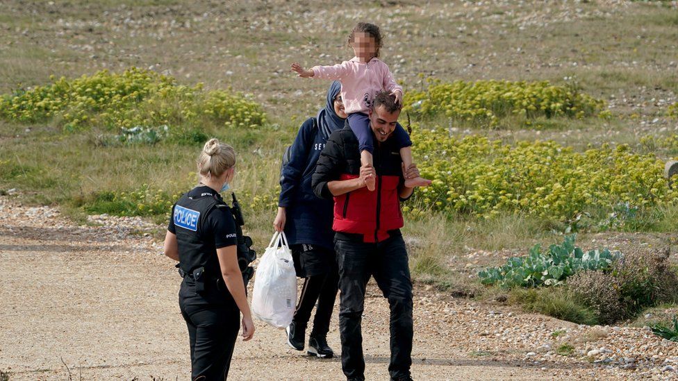 Migrants being escorted by a police officer